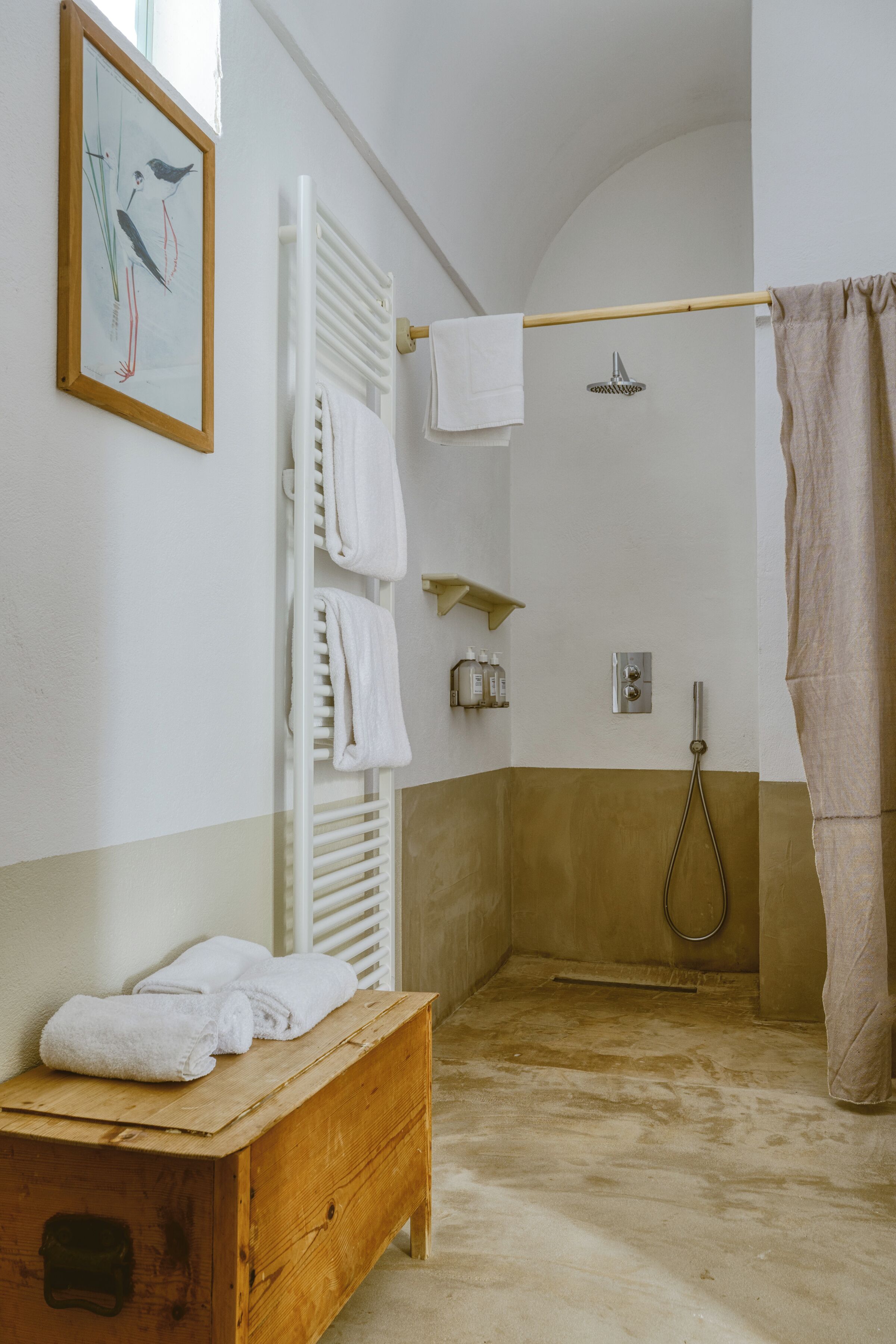 Ein Badezimmer mit einer Holzbank, einer Dusche mit beiger Duschvorhang und einem Wandhandtuchhalter.