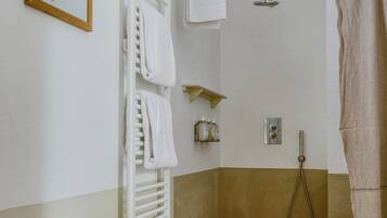 Ein Badezimmer mit einer Holzbank, einer Dusche mit beiger Duschvorhang und einem Wandhandtuchhalter.