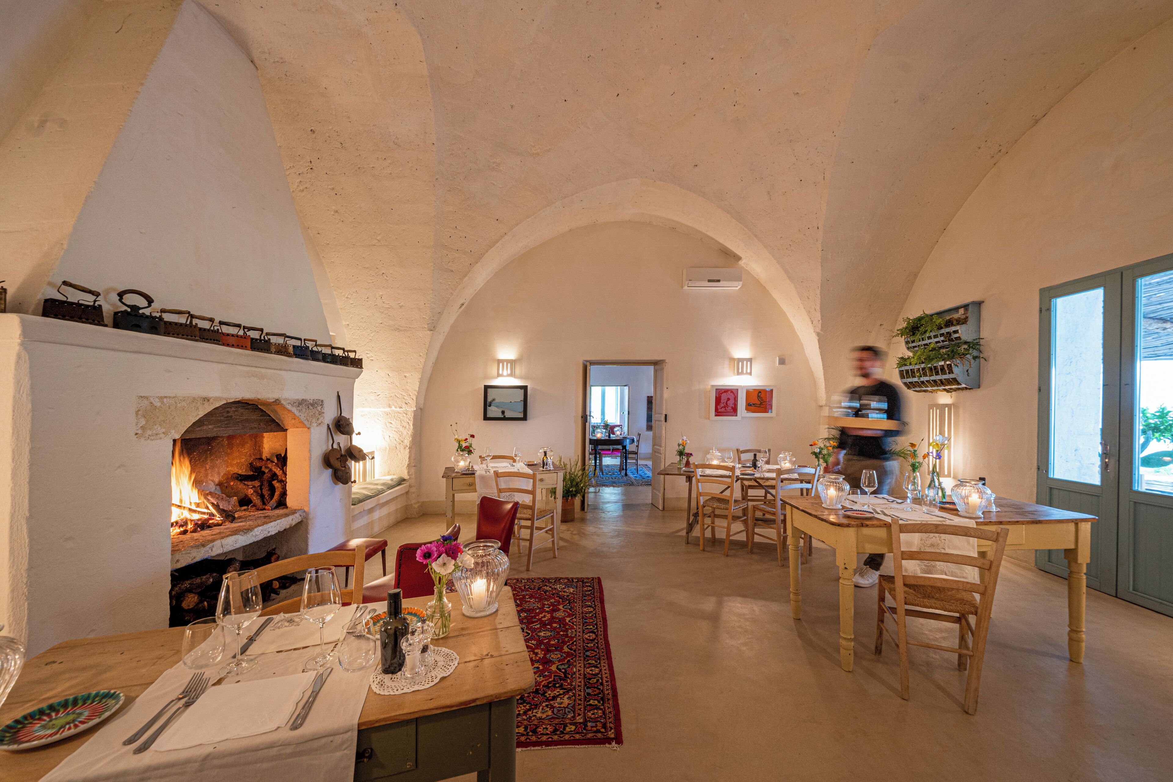 A dining area with a fireplace, wooden tables, chairs, and a view of the dining room.