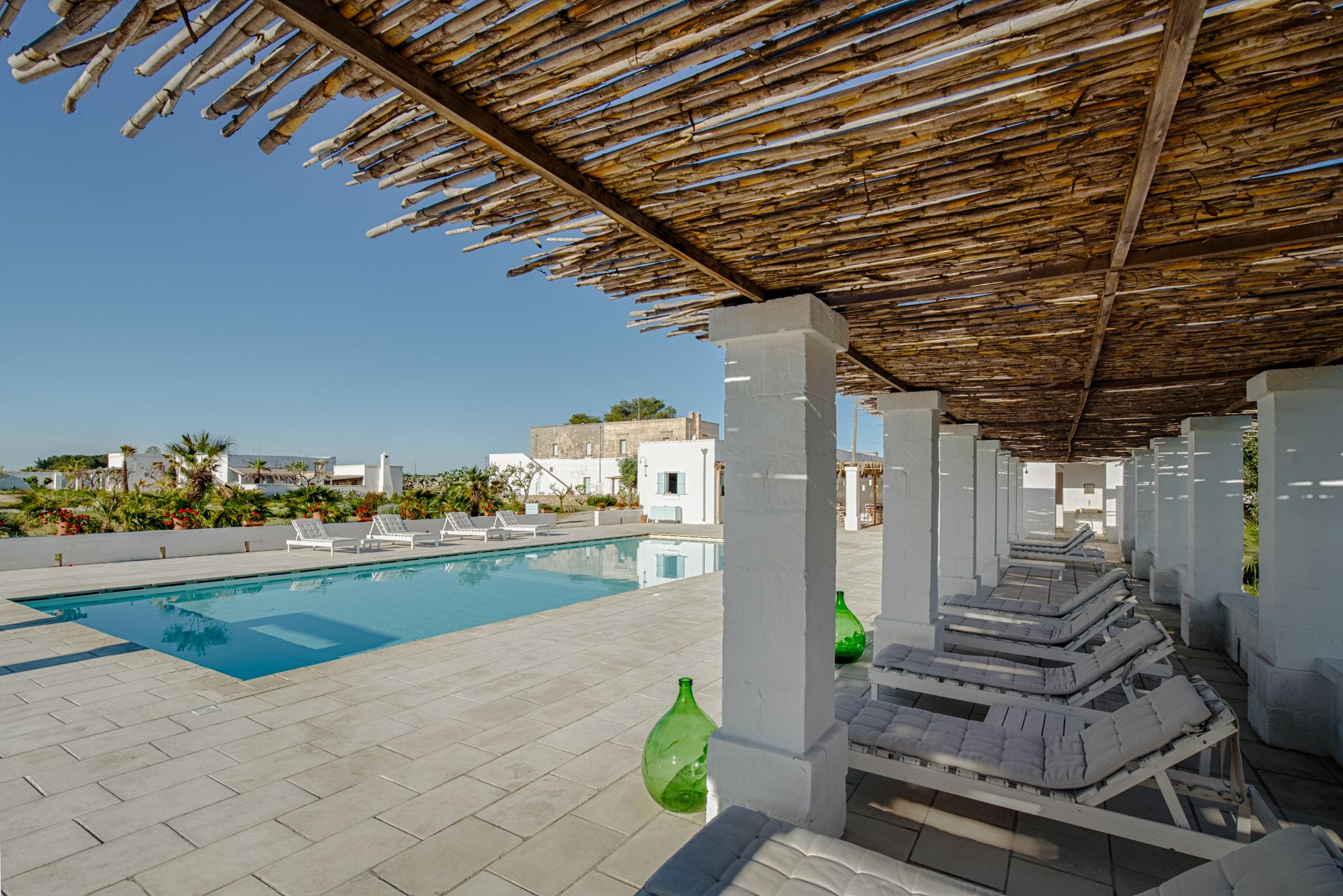 A rooftop pool area with lounge chairs and a clear blue pool.