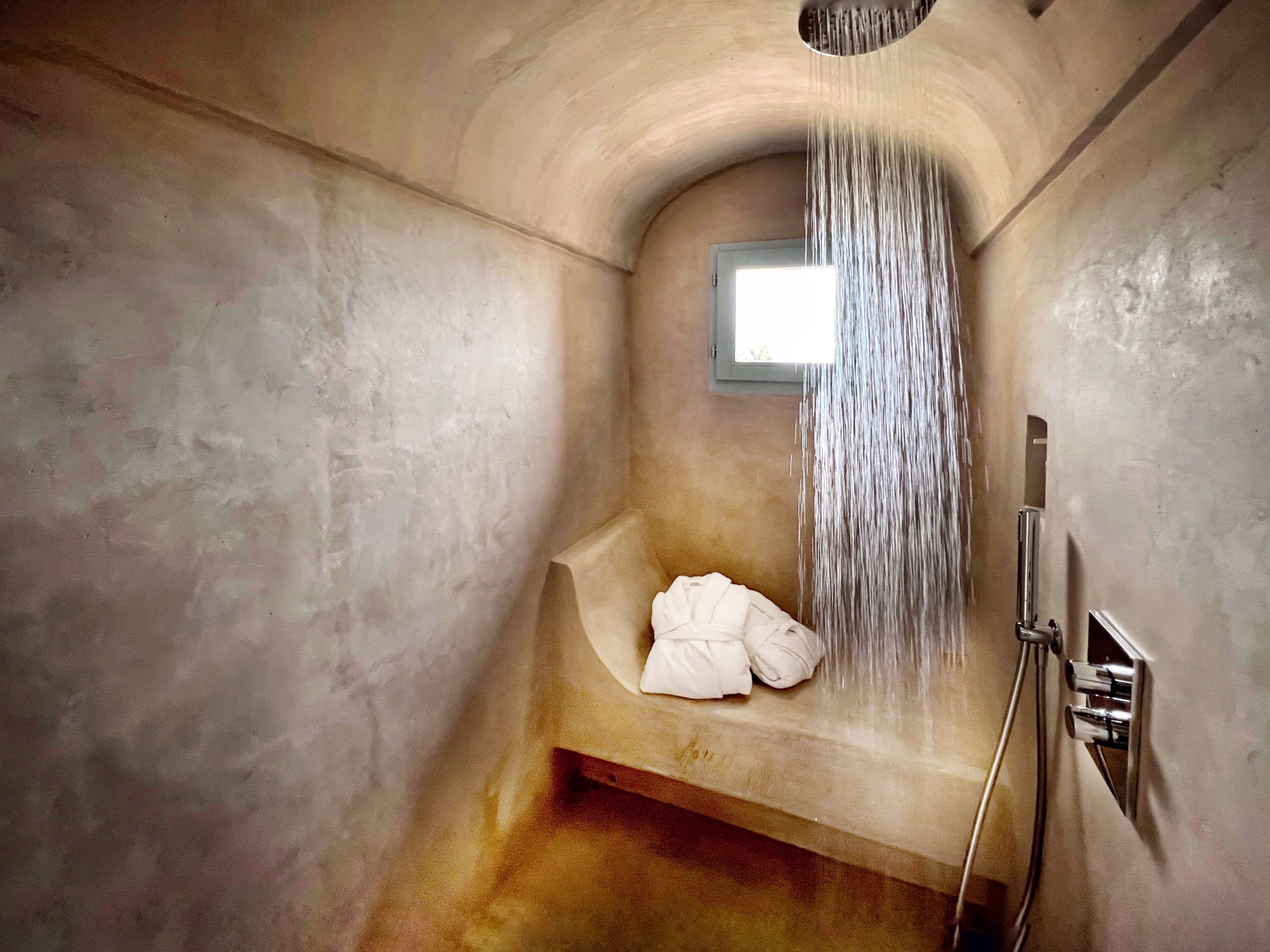 Une baignoire avec un pommeau de douche, une serviette et une fenêtre.