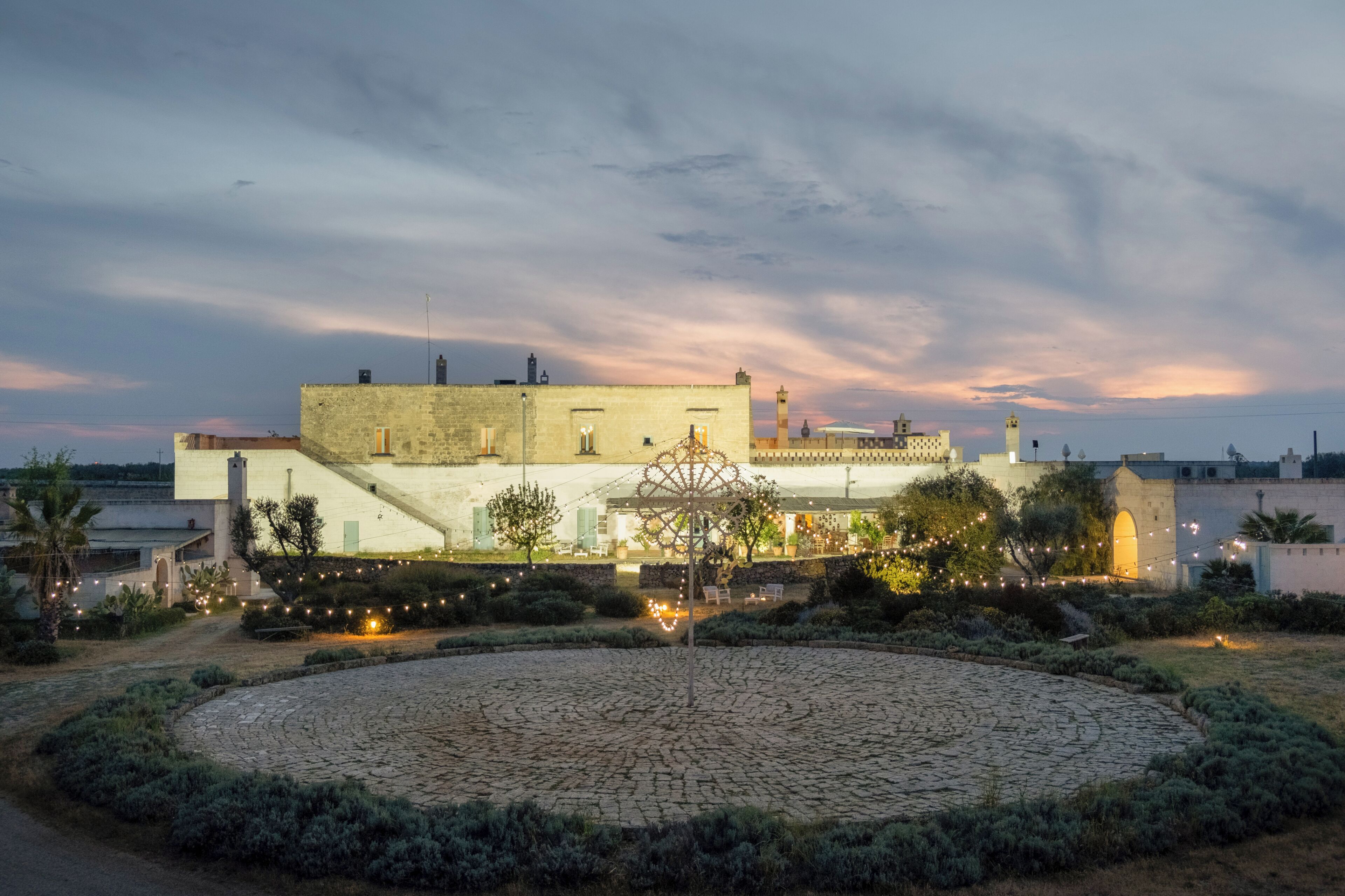 A historic building with a courtyard, stone pavement, and string lights.