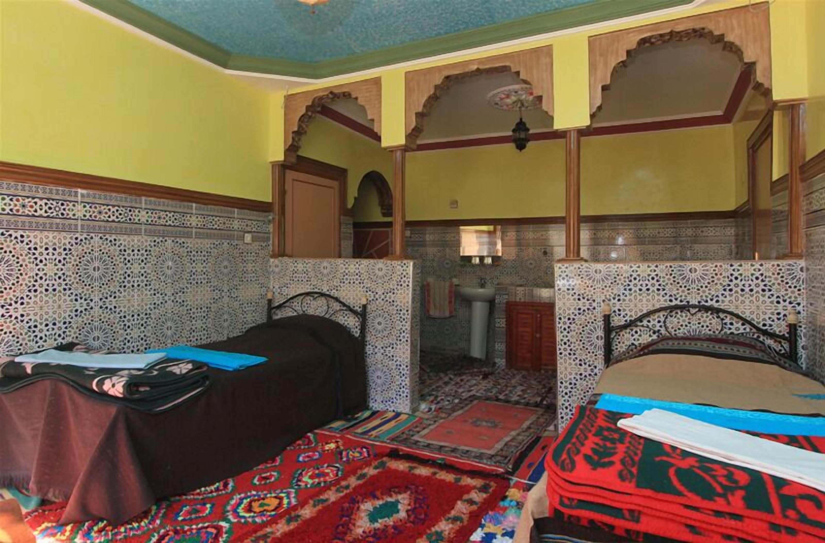 A room with two beds, patterned walls, and a traditional archway.