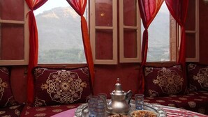 Habitaci ón tradicional con un conjunto de sofá, una mesa con una bandeja de comida y bebidas, y vistas a montañas desde la ventana.