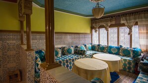 Un interior tradicional marroquí con un sofá estampado, una mesa redonda y elaborados trabajos en azulejos.