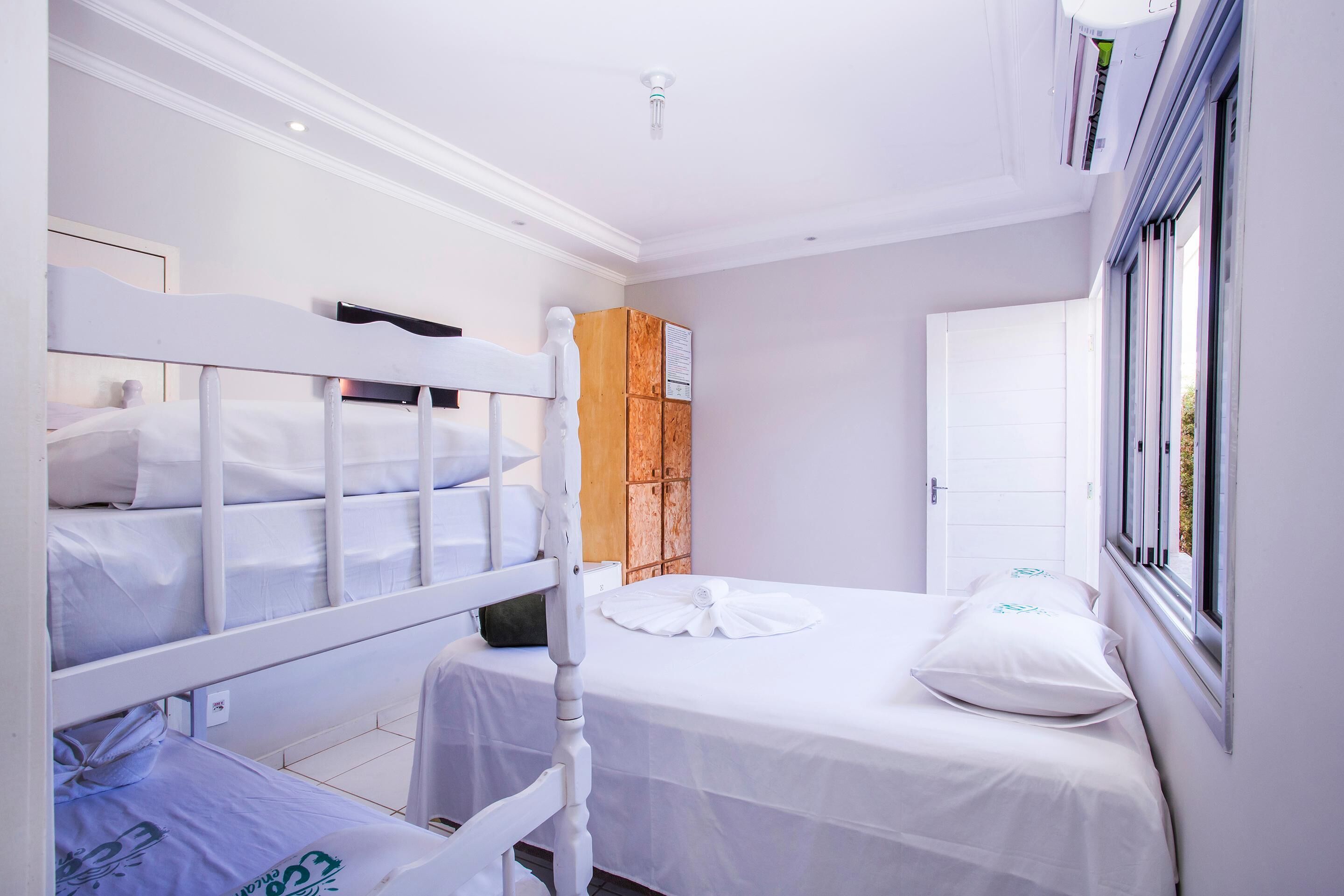 Ein Schlafzimmer mit Etagenbetten, einem Holzschrank, einer Tür und einem Fenster.