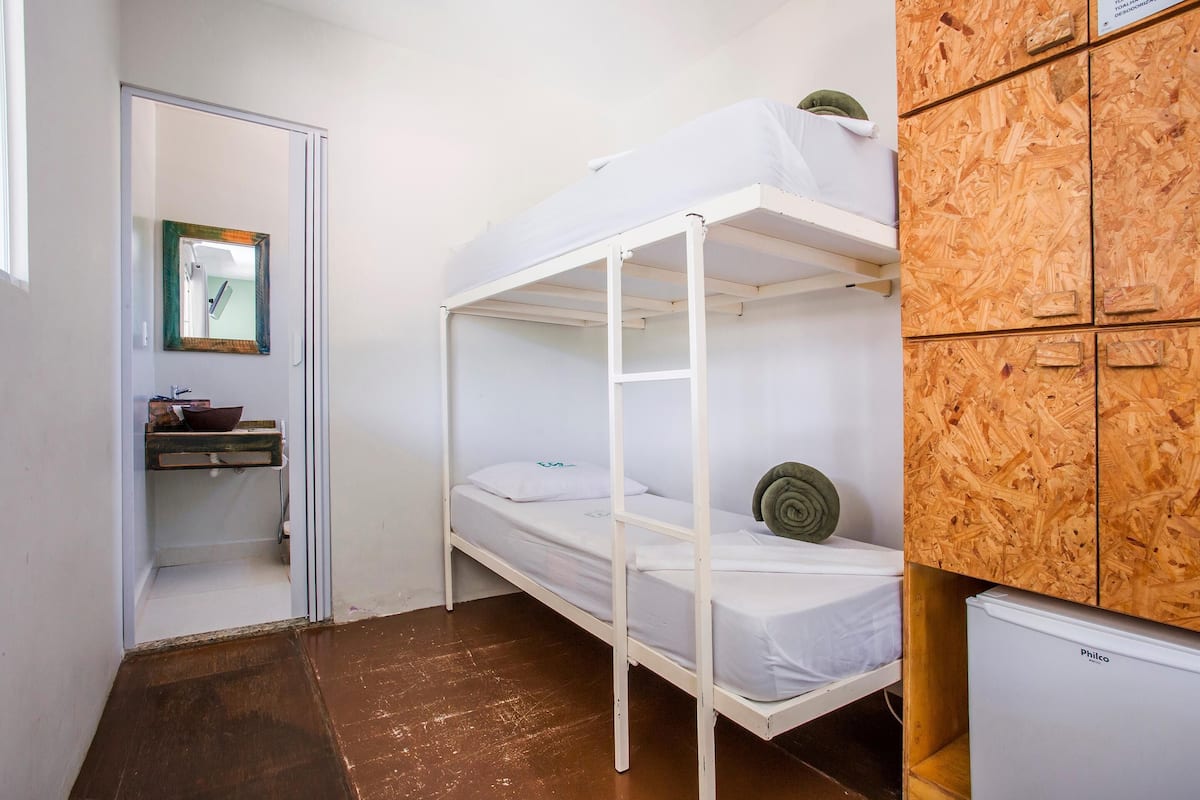 A bunk bed room with a wooden cabinet, a small sink, and a mirror.