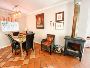 Un coin repas avec une table dressée pour quatre personnes, entourée de chaises, d’une cheminée et d’œuvres d’art accrochées au mur.