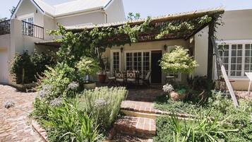 A house with a covered patio, potted plants, and a brick pathway leading to the entrance.