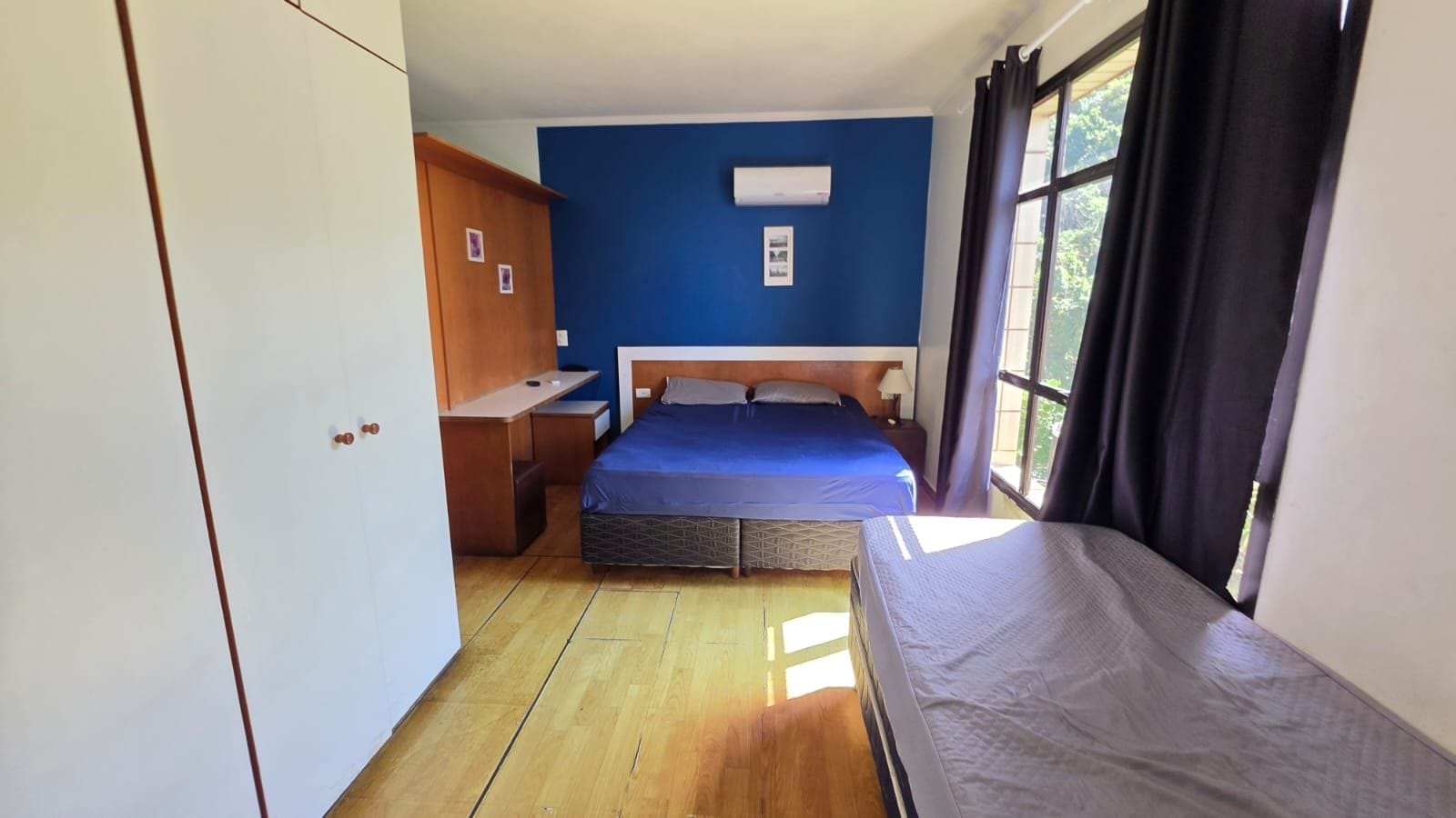 Ein kleines Zimmer mit einem Bett, einem Schreibtisch und einem Kleiderschrank.