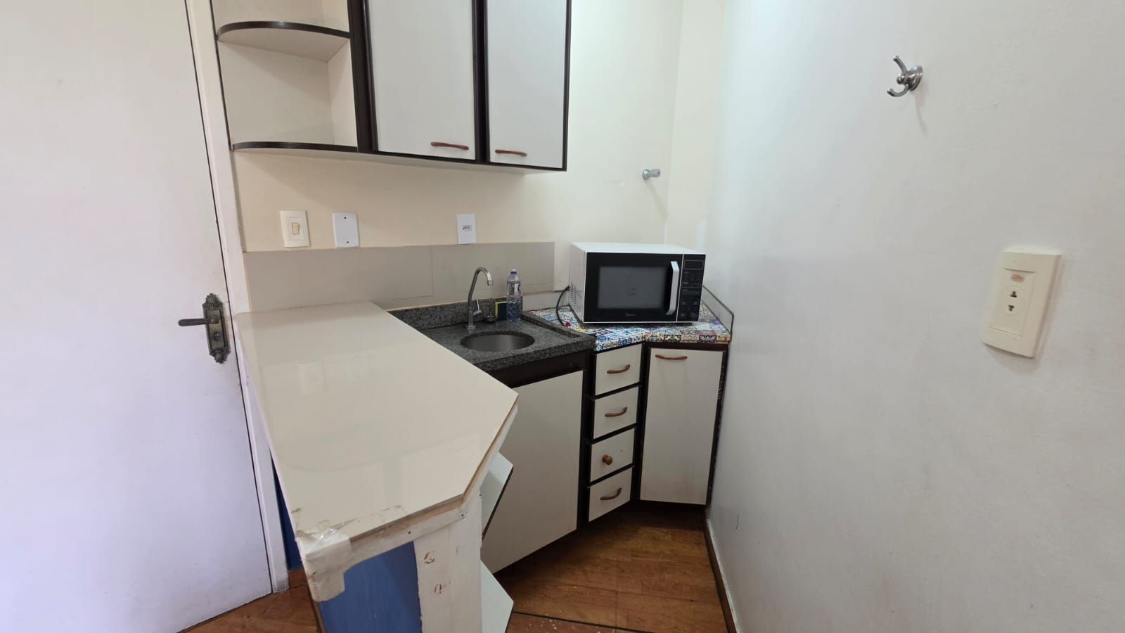 A compact kitchen with a microwave, sink, and cabinets.
