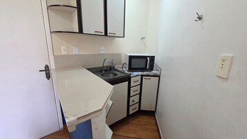 Uma cozinha compacta com micro-ondas, pia e armários.