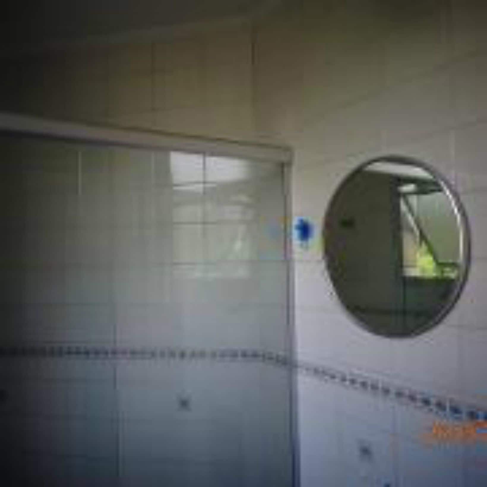 A bathroom with white tiles, a round mirror, and a visible door.
