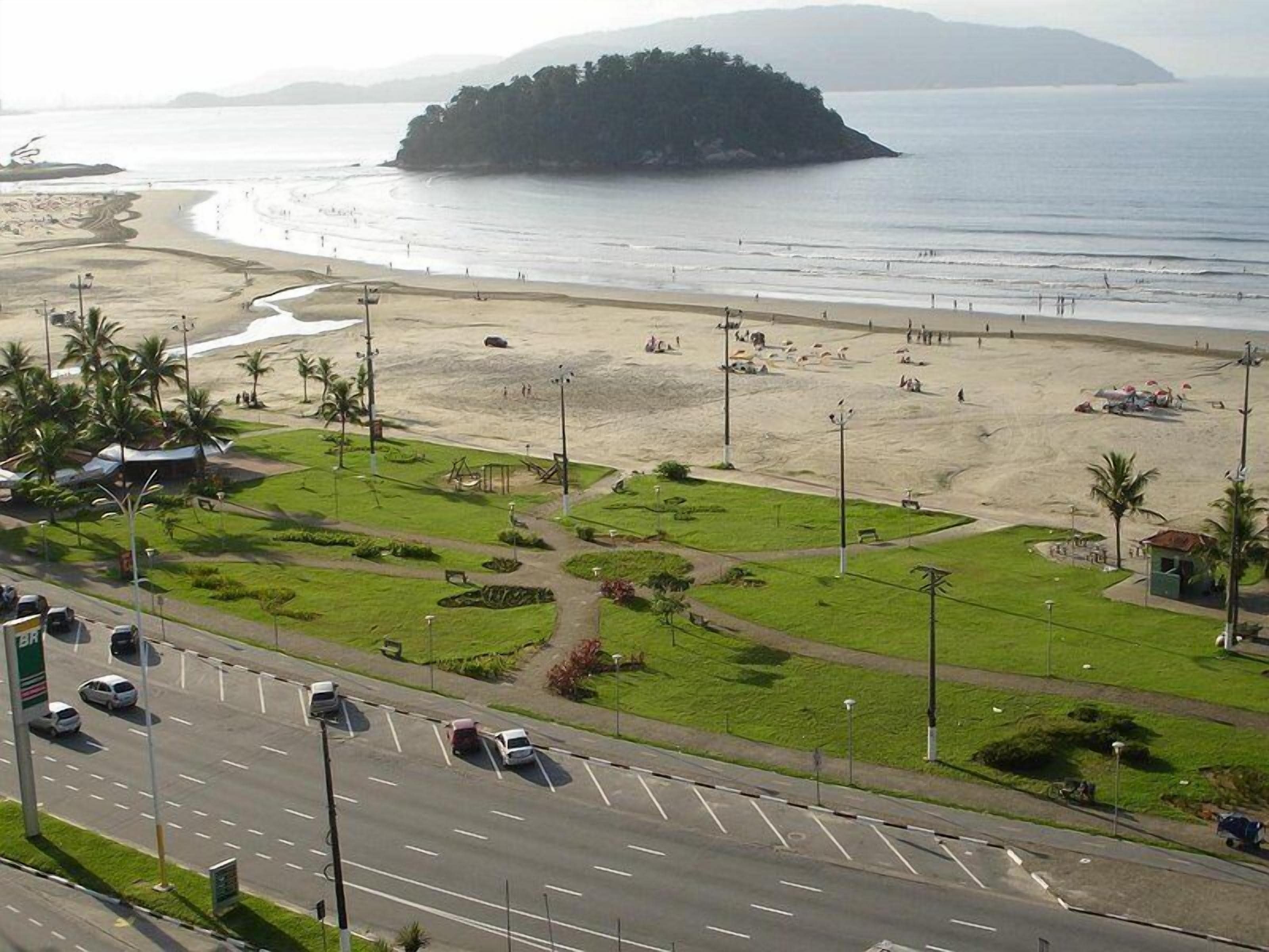 Uma estrada costeira com uma praia e uma pequena ilha ao longe.
