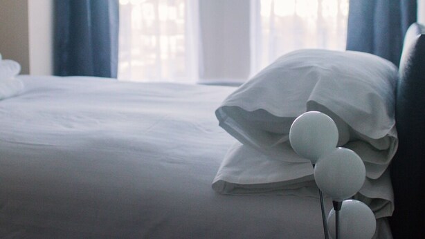 Een bed met witte beddengoed en een kussen met een witte decoratieve versiering.
