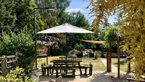 A garden patio with a wooden table and benches, surrounded by a gravel path and greenery. - Woodpaddock B&B (March)