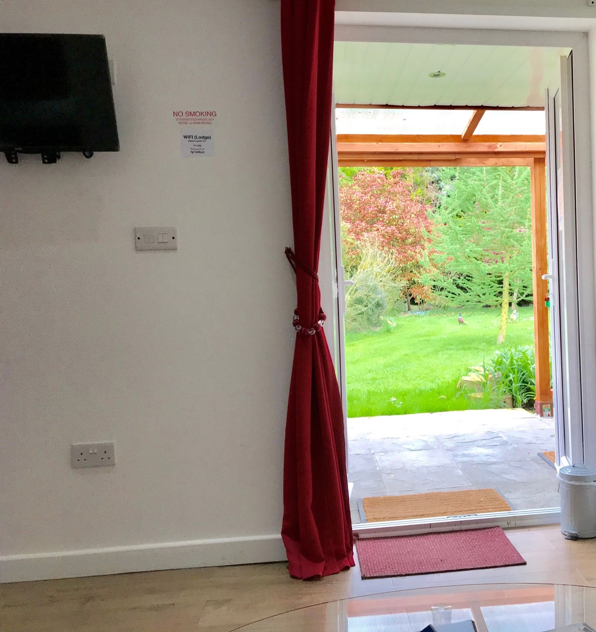 A room with a red curtain, a TV mounted on the wall, and a sign indicating no smoking.