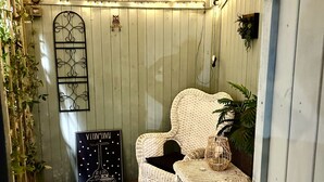 A cozy room with a wicker chair, a zebra-patterned rug, and string lights on the ceiling. - Woodpaddock B&B (March)