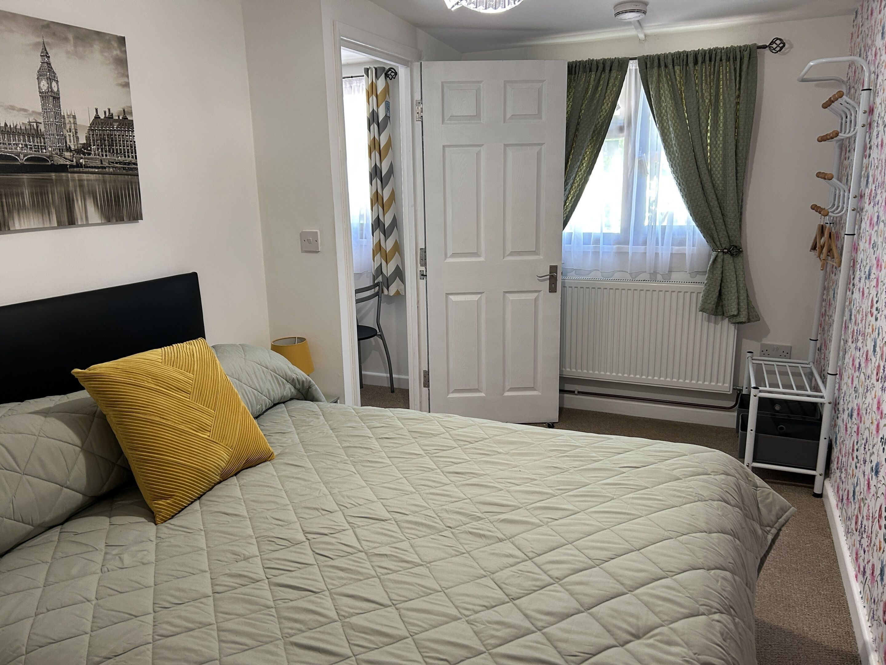 A bedroom with a bed, a radiator, a door, and a window with curtains.