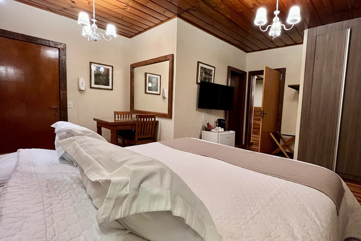 A hotel room with a bed, a desk, a chair, a television, and a wardrobe.