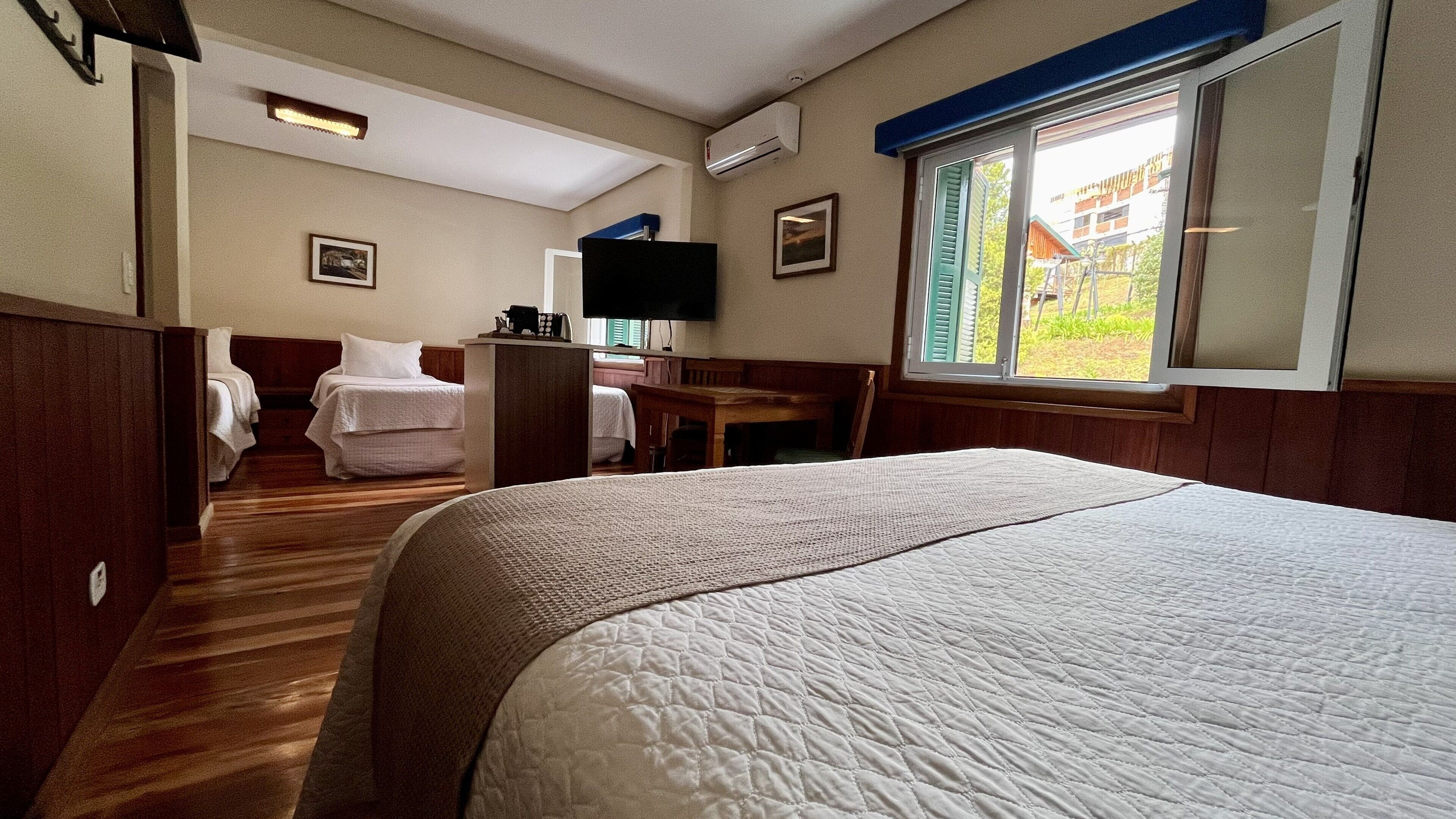 Une chambre d’hôtel équipée d’un lit, d’un bureau, d’une chaise, d’une télévision et d’une fenêtre donnant sur l’extérieur.