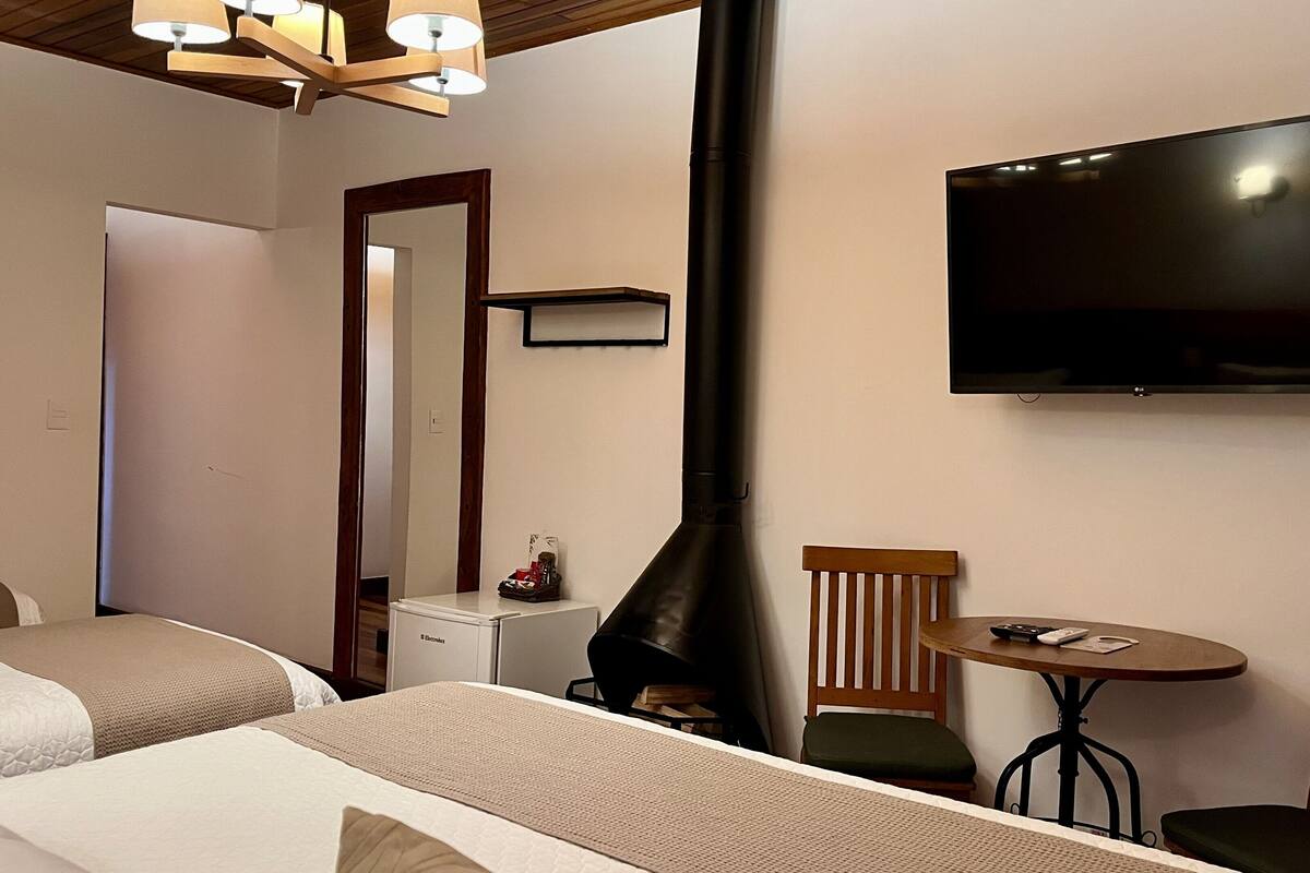 A hotel room with two beds, a TV, a small table, and a chair.