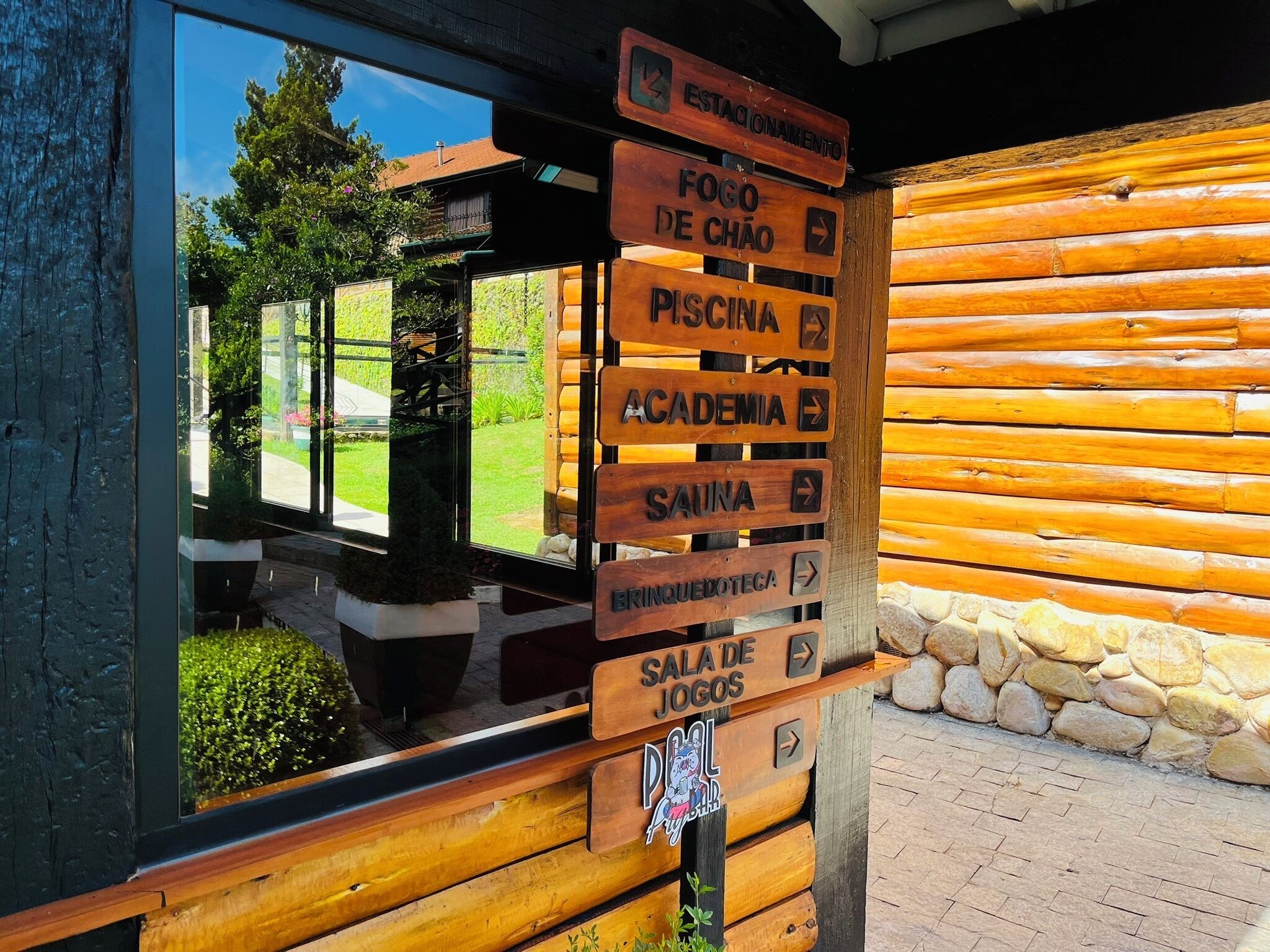 A wooden signpost with directions to various amenities including a sauna, pool, and games room.
