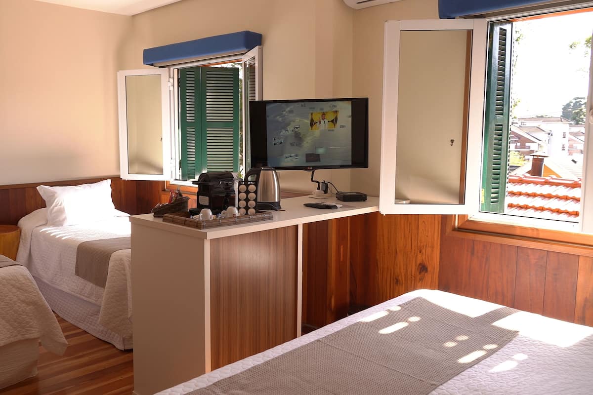 A hotel room with two beds, a desk with a computer, coffee maker, and a TV.
