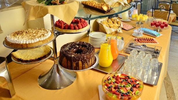 Una mesa de buffet con diversos postres, frutas y bebidas.