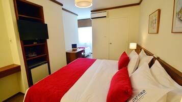 Una habitación de hotel con cama, televisión, escritorio y armario.