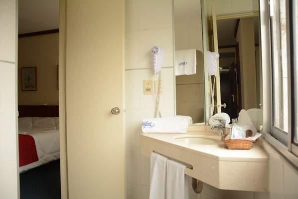 A hotel bathroom with a sink, mirror, hairdryer, and towel rack. - Oxford Hotel (Montevideo)