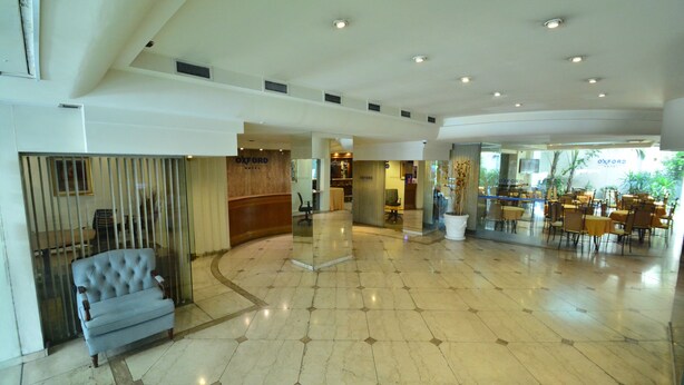 A spacious lobby with a marble floor, a seating area with a tufted armchair, and a reception desk. - Oxford Hotel (Montevideo)