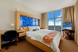 Habitación de hotel con cama, escritorio, silla, televisor y un ventanal con vistas.