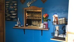 A reception desk with a 'Welcome' sign, a fish poster, and a mirror. - Tarragon Motel (Marinette)