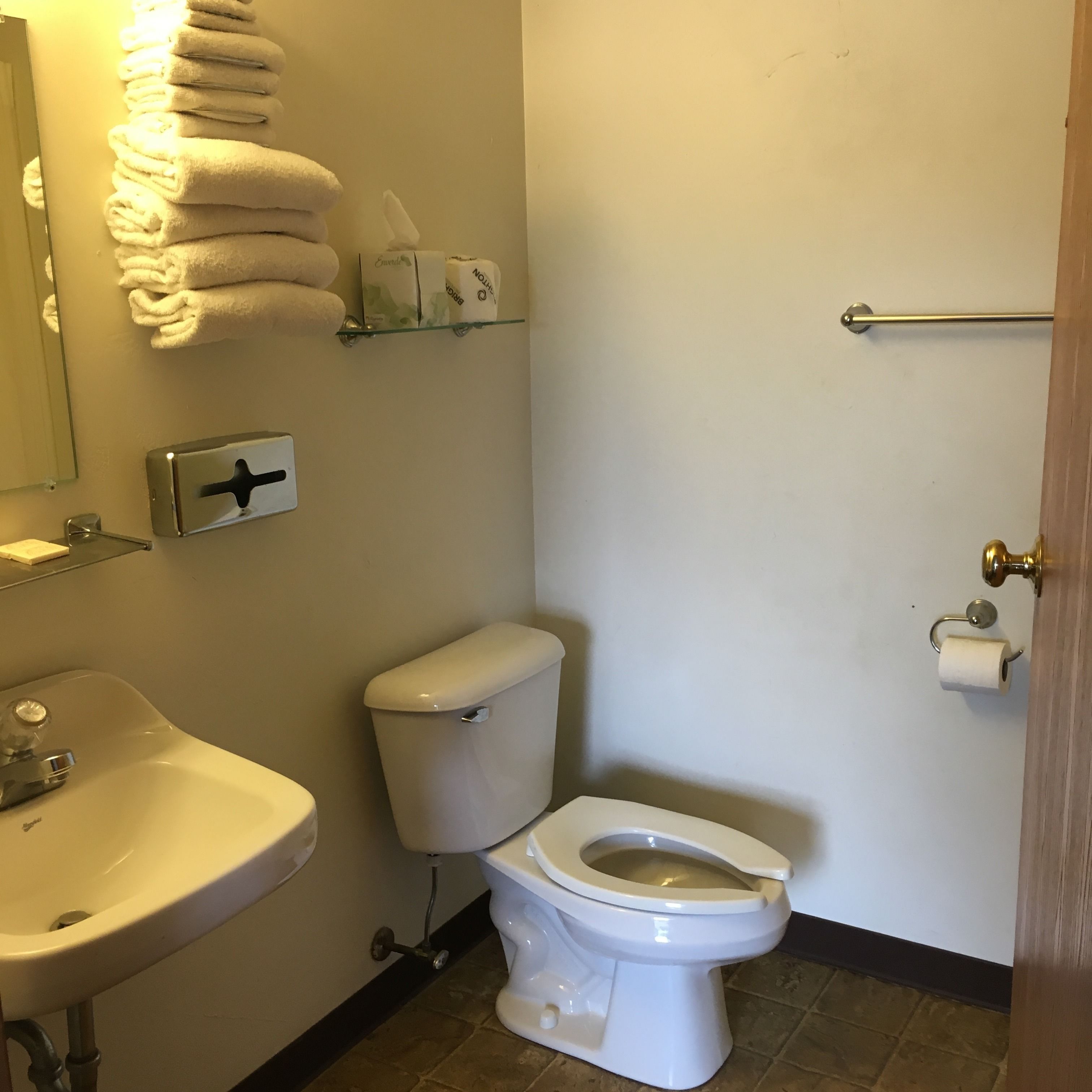 Une salle de bain avec des toilettes, un lavabo et des serviettes pliées.