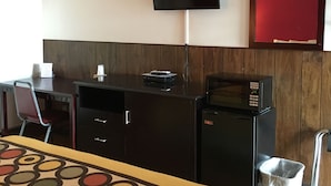 A hotel room with a bed, a desk, a television, a microwave, and a trash bin. - Tarragon Motel (Marinette)