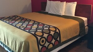 A bed with a patterned bedspread, white pillows, and a wooden headboard. - Tarragon Motel (Marinette)