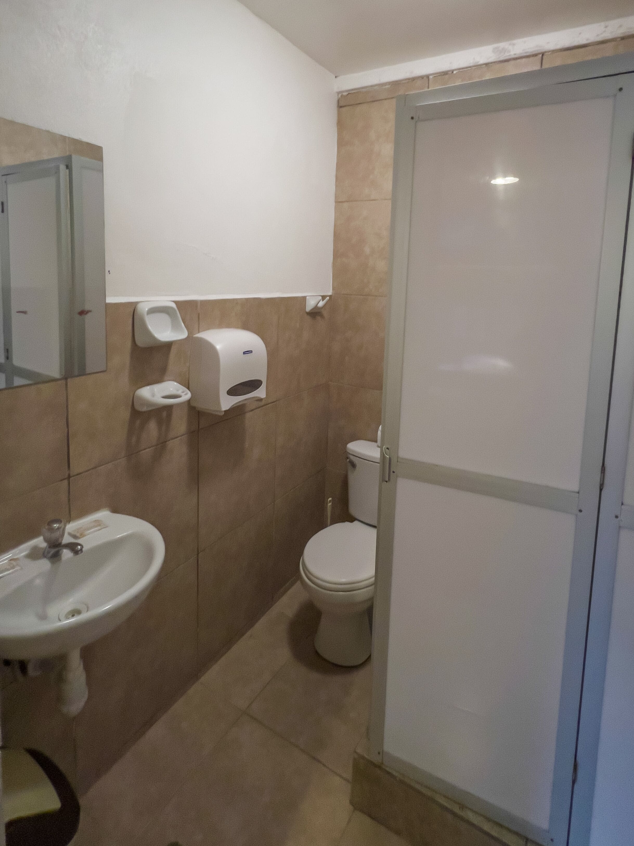 A bathroom with a sink, toilet, and a mirror.