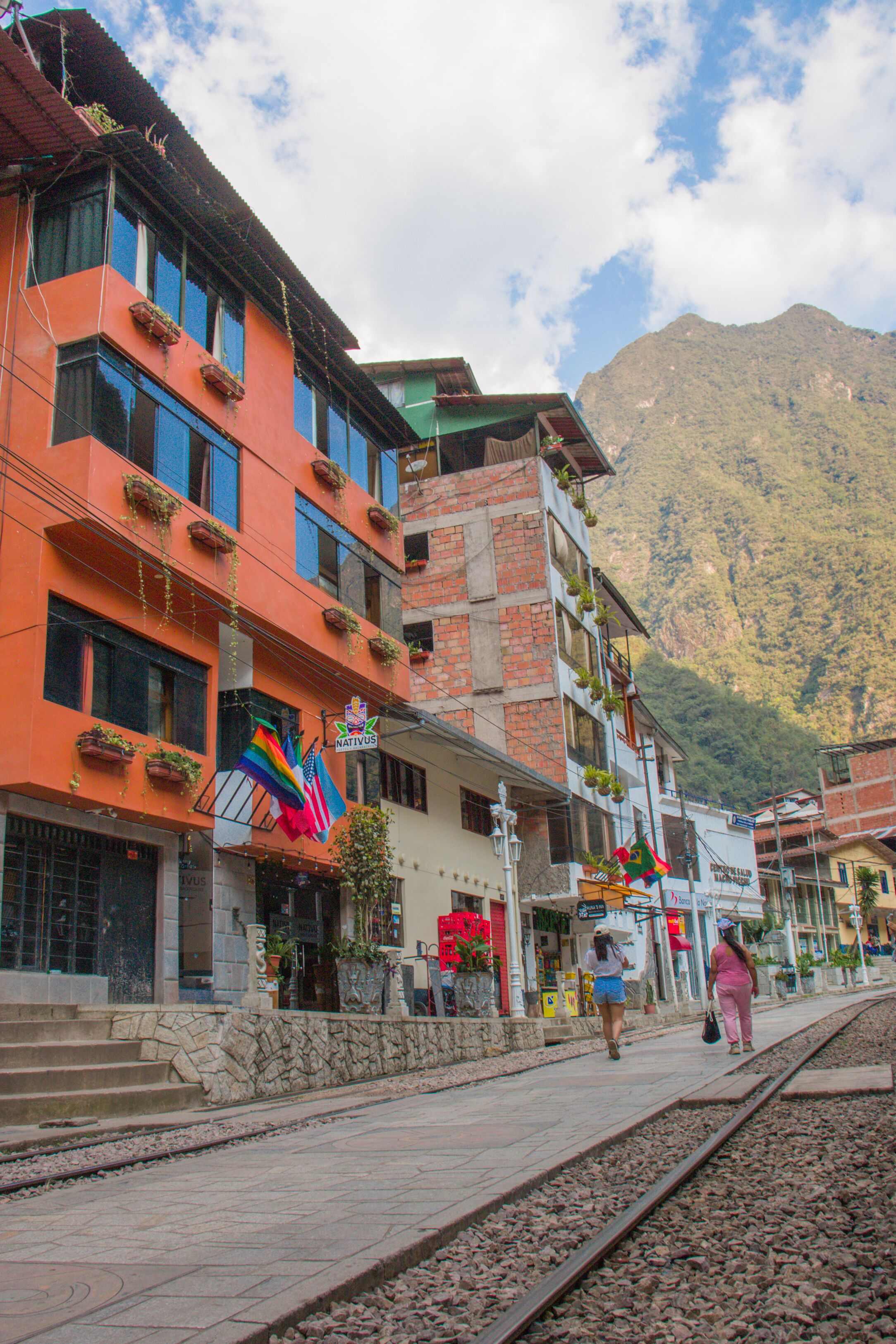 A street with buildings, a train track, and mountains in the background.