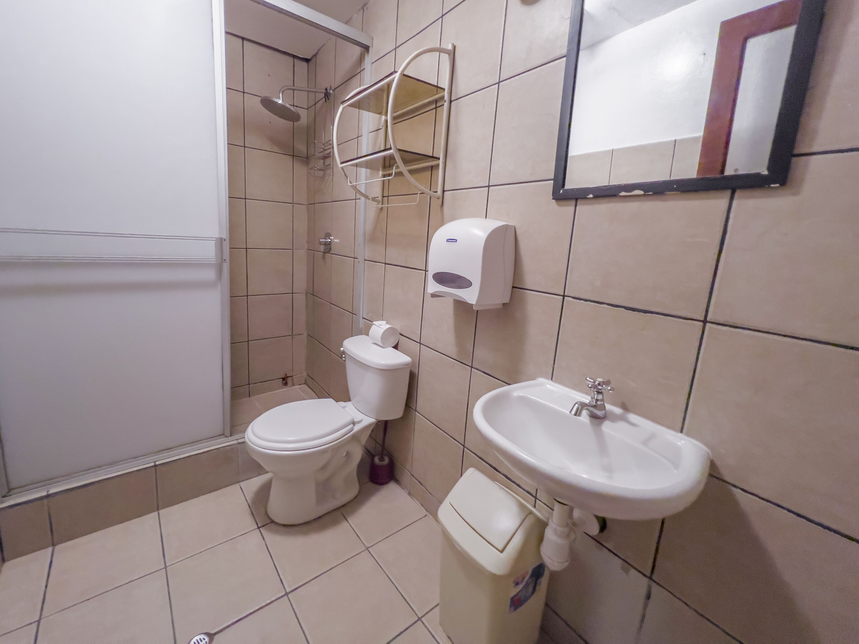 Un baño con inodoro, lavamanos y secamanos.