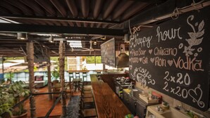 A restaurant with a chalkboard menu listing items like 'Pisco Sour' and 'Chicano'. There are wooden tables and chairs, and a bar area with a counter. - Nativus Hostel Machu Picchu (Machu Picchu)