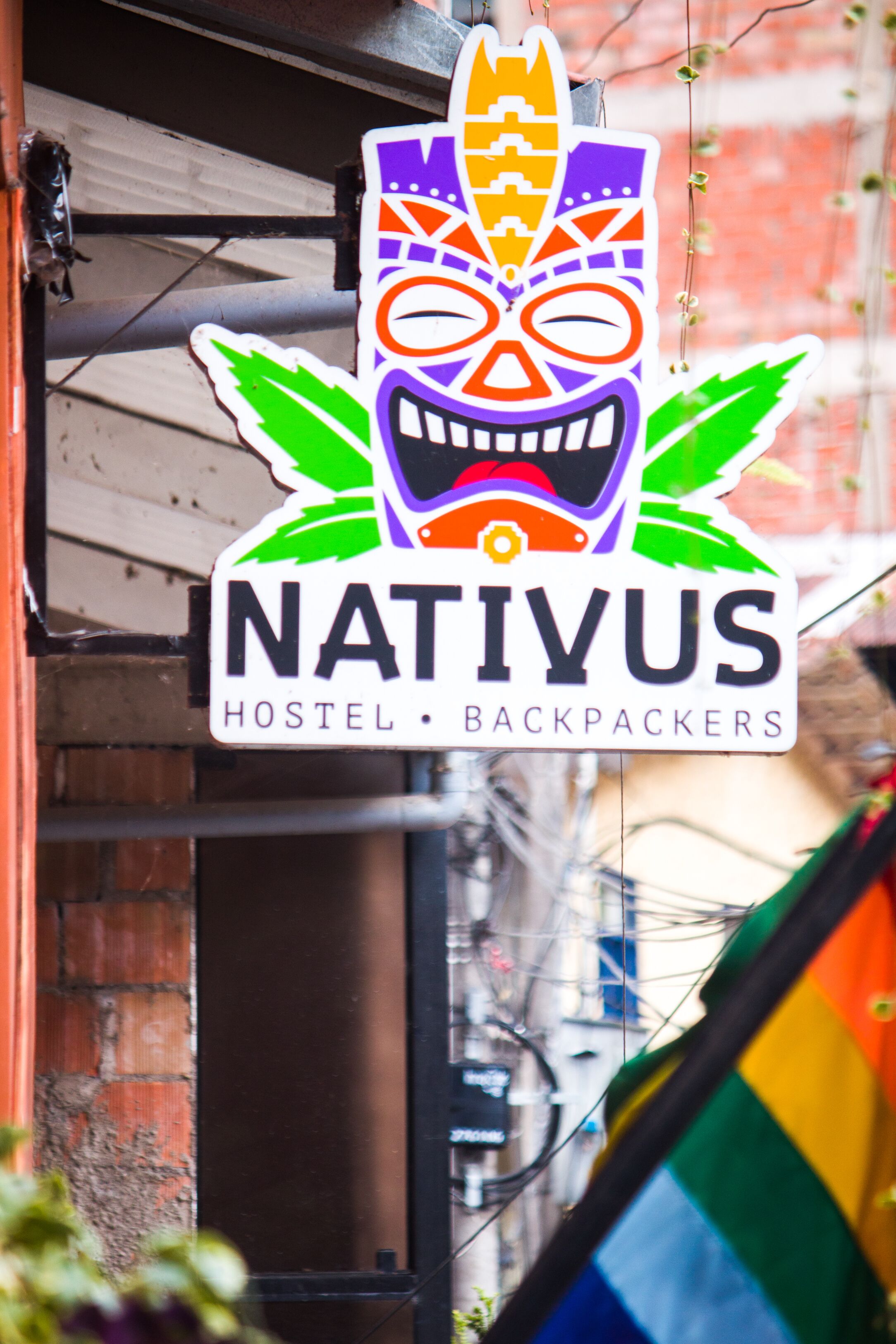 A hostel sign with a colorful mask design and the name "NATIVUS HOSTEL BACKPACKERS".