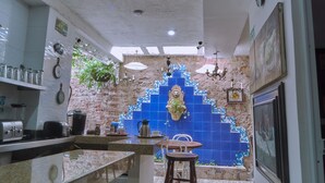 Une cuisine avec un dosseret carrelé, une machine à café et une plante suspendue.