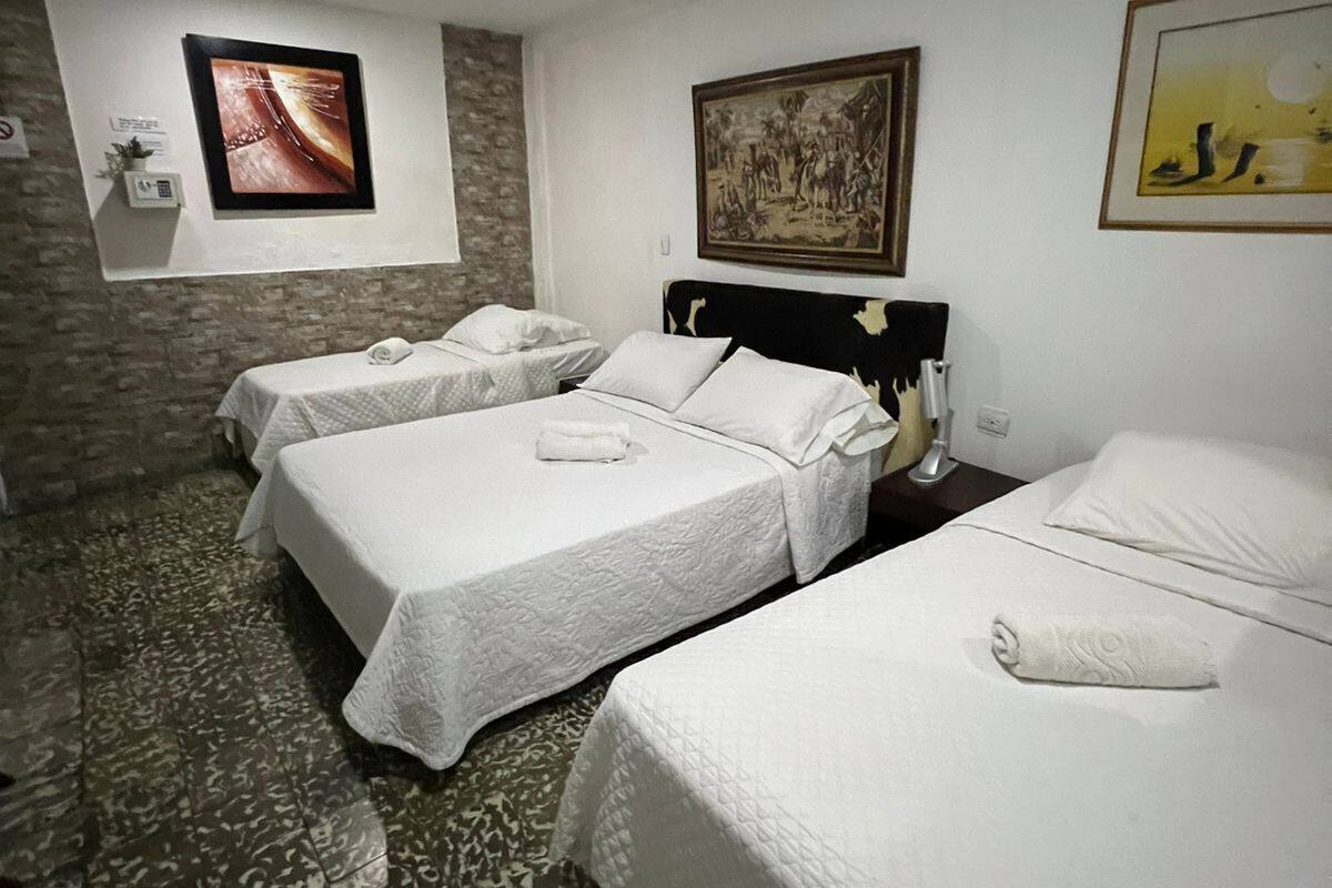 Habitación de hotel con dos camas, pared de piedra y obras de arte en las paredes.
