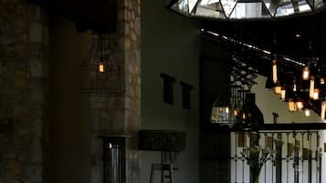 Comedor con mesa de vidrio, sillas y pared de piedra.