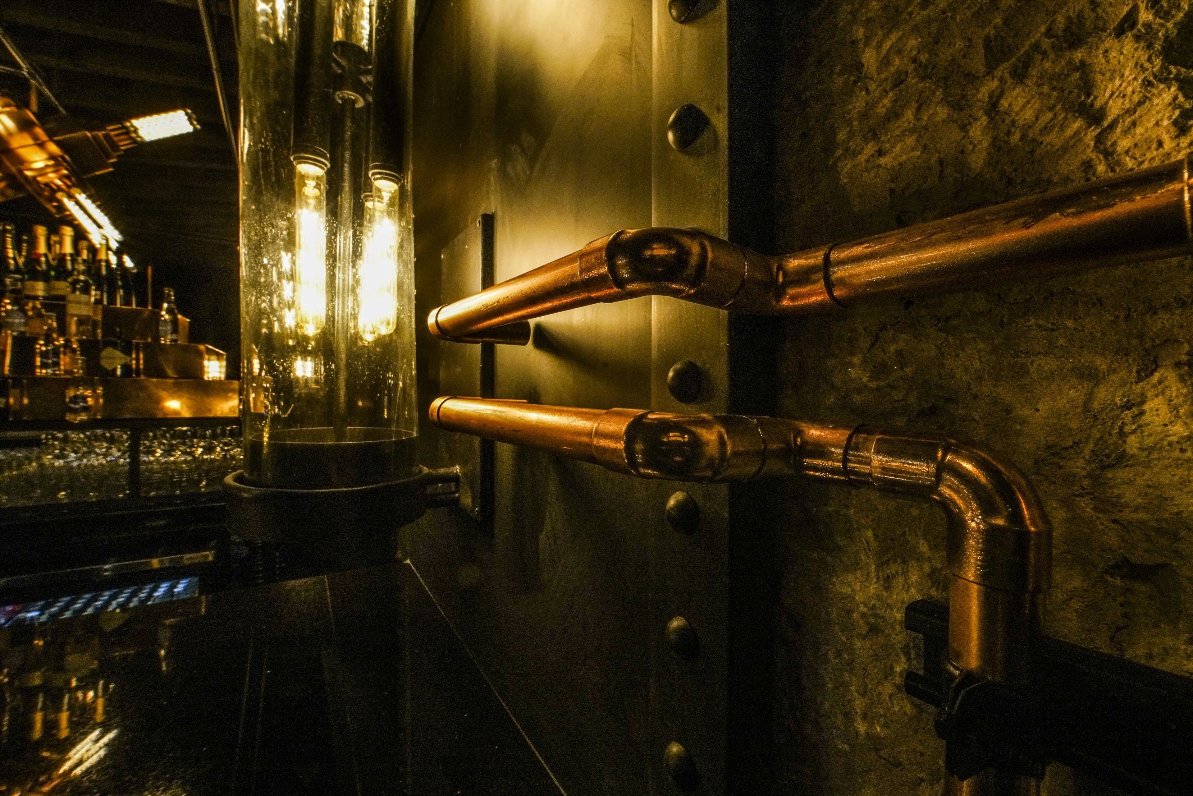A bar area with copper pipes and glassware.
