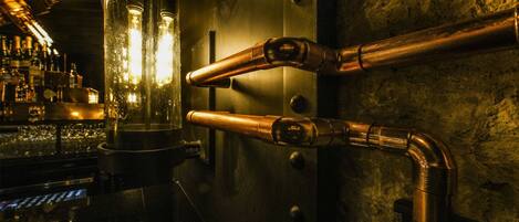 A bar area with copper pipes and glassware.