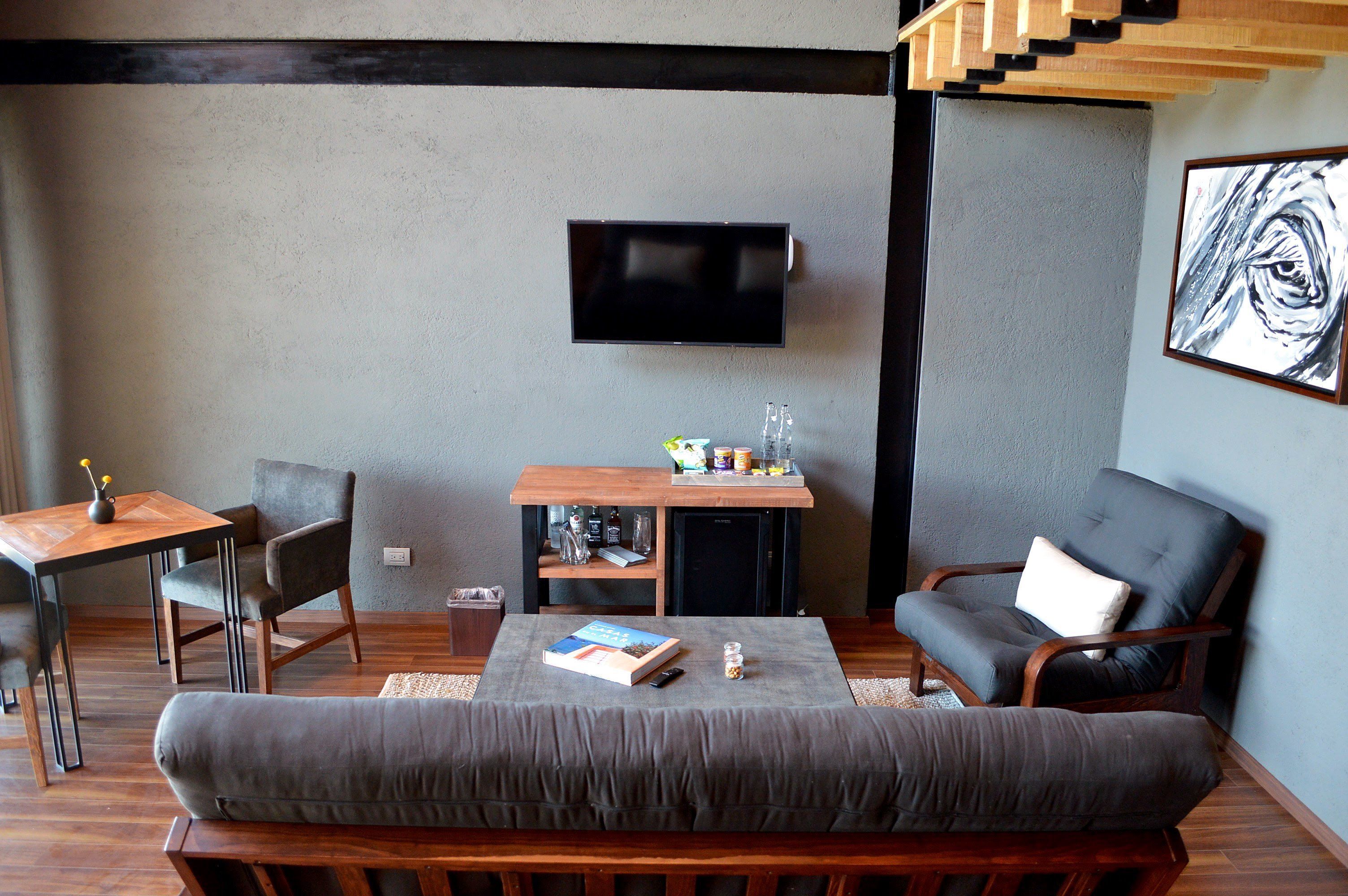 A modern living room with a sofa, a chair, a small table, and a TV mounted on the wall.
