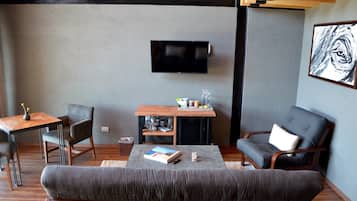 A modern living room with a sofa, a chair, a small table, and a TV mounted on the wall.