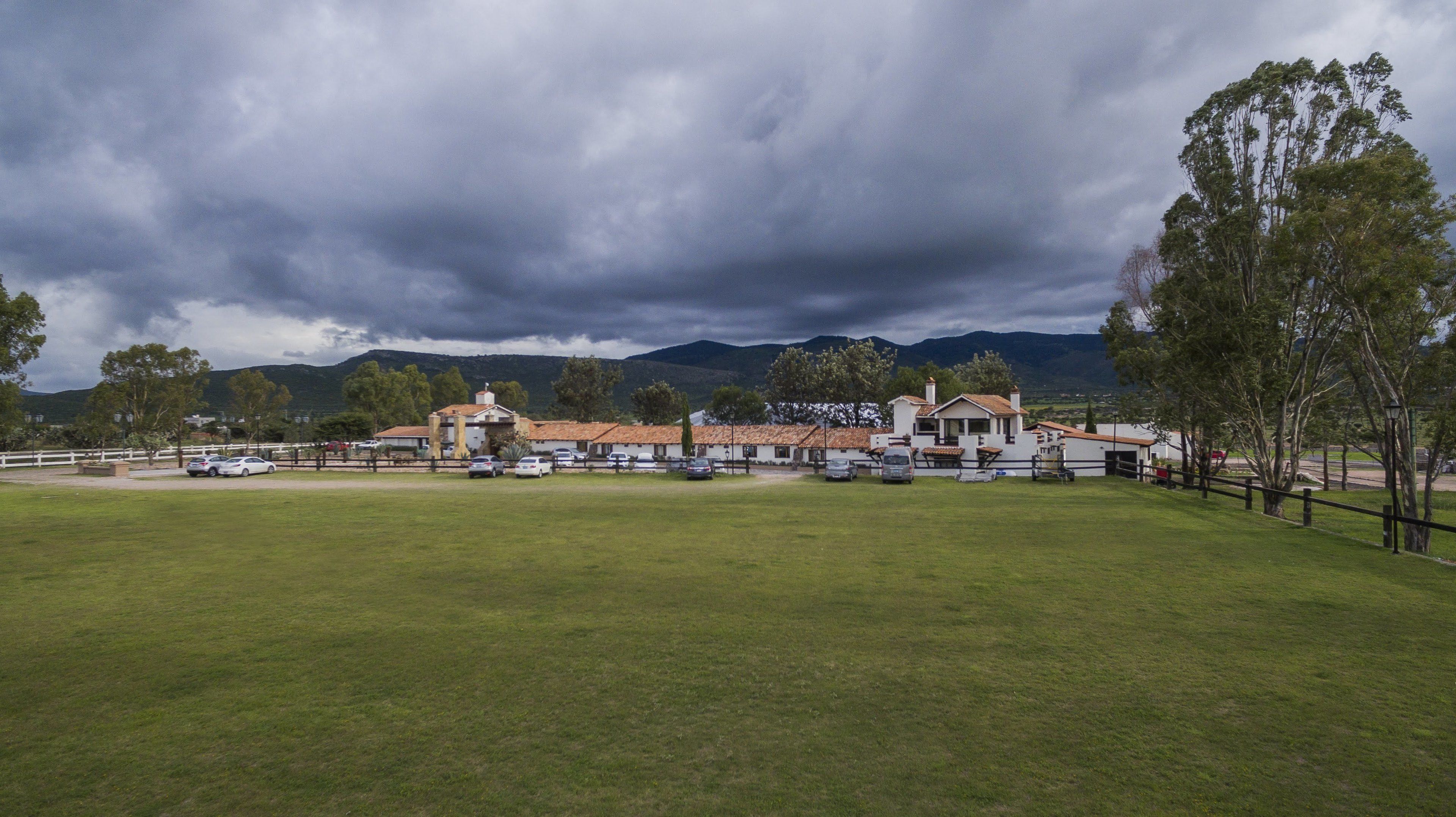 A hotel with multiple buildings, a parking lot, and a grassy field.